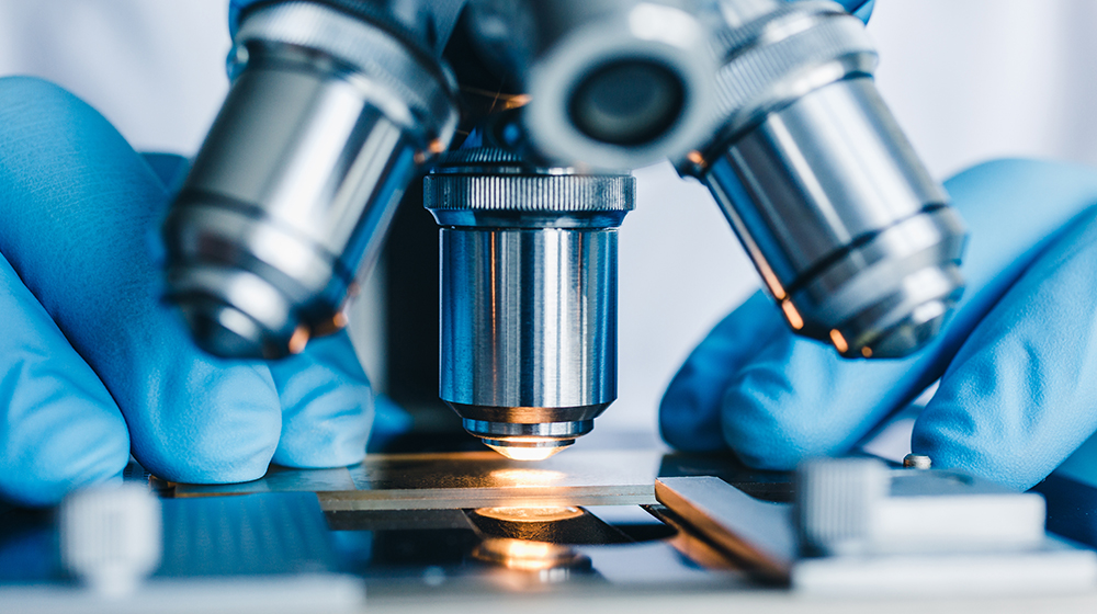 Close-up shot of microscope with metal lens at laboratory for medical equipment manufacturing page.